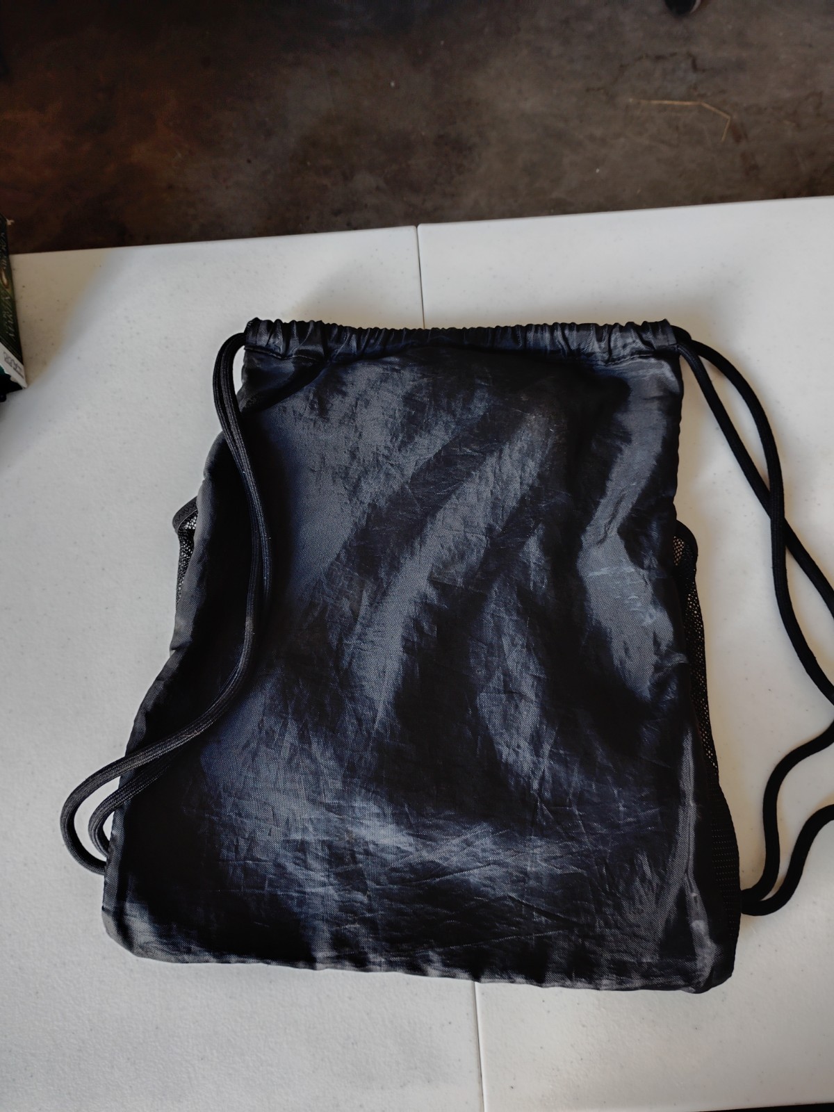Black PUMA Evercat Equinox cinch bag with a front zippered pocket and mesh side